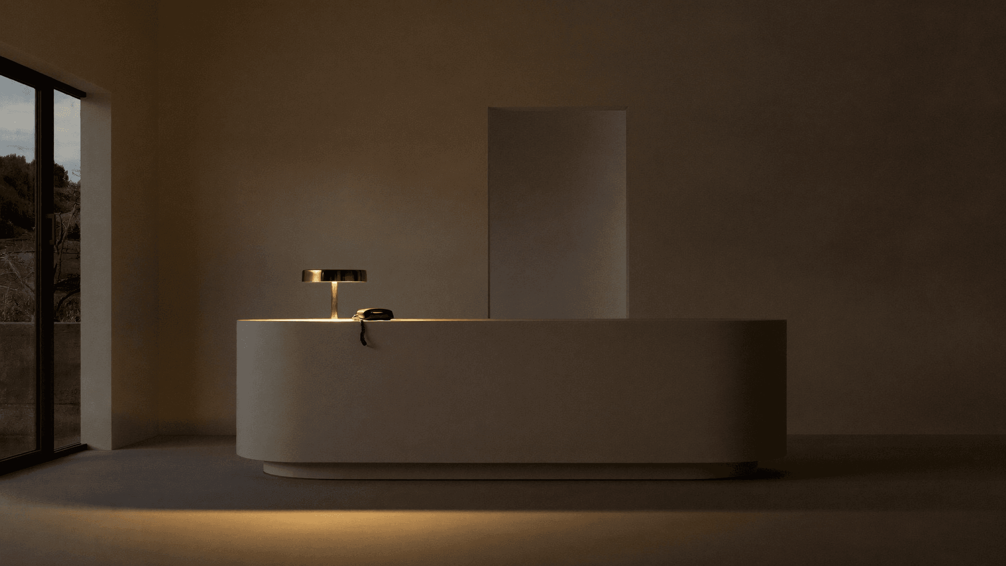 Premium minimalist office reception at dusk with a single desk phone under warm lamp light